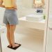 Pregnant woman checks weight in modern bathroom. Reflecting on health and motherhood.