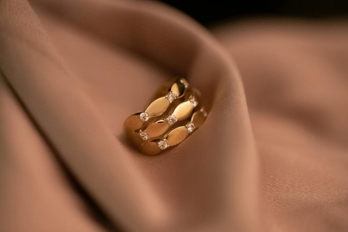 Luxurious gold ring featuring diamonds, delicately resting on a soft fabric, exuding elegance and sophistication.