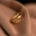 Luxurious gold ring featuring diamonds, delicately resting on a soft fabric, exuding elegance and sophistication.